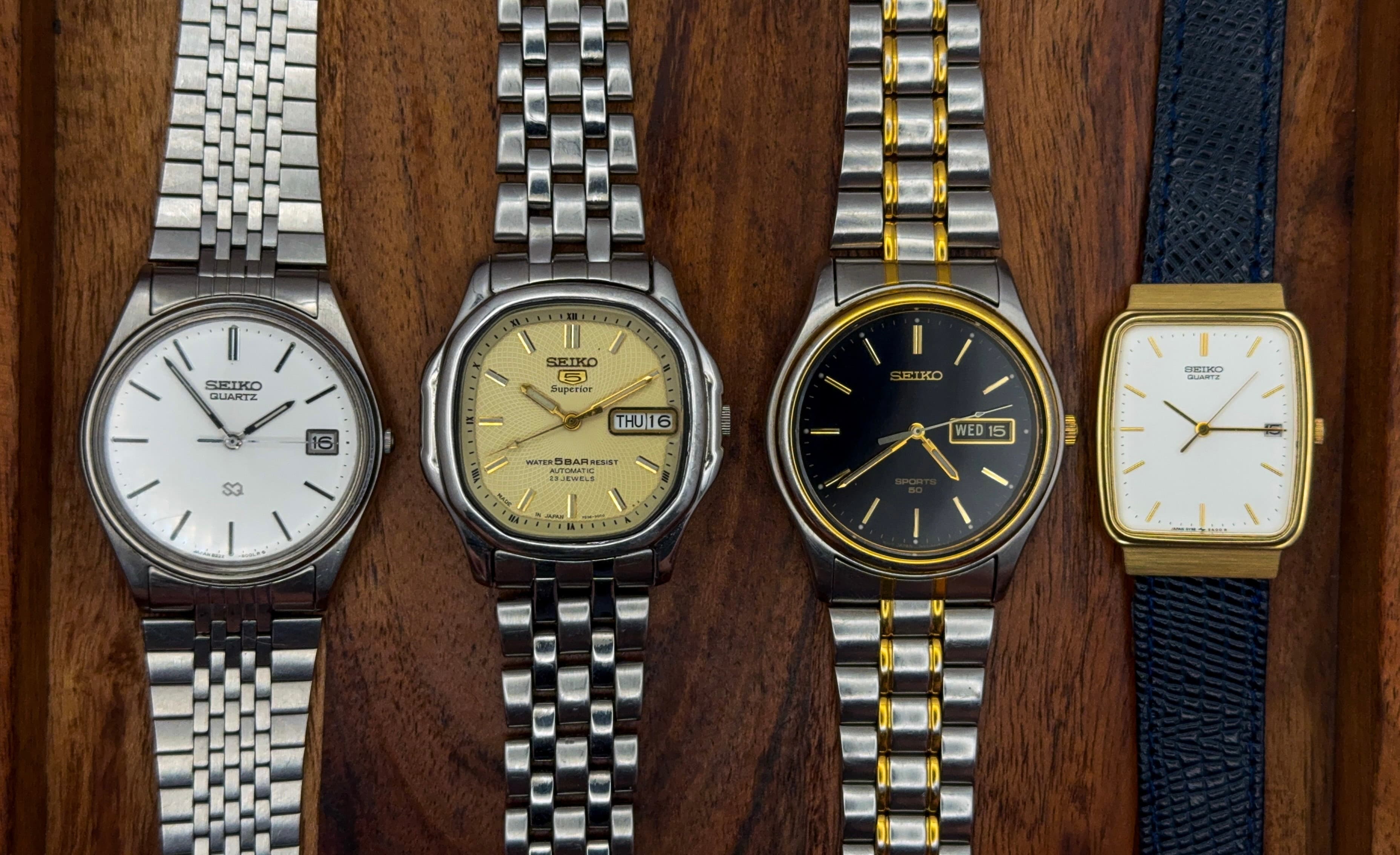 Four vintage watches arranged on a wood surface